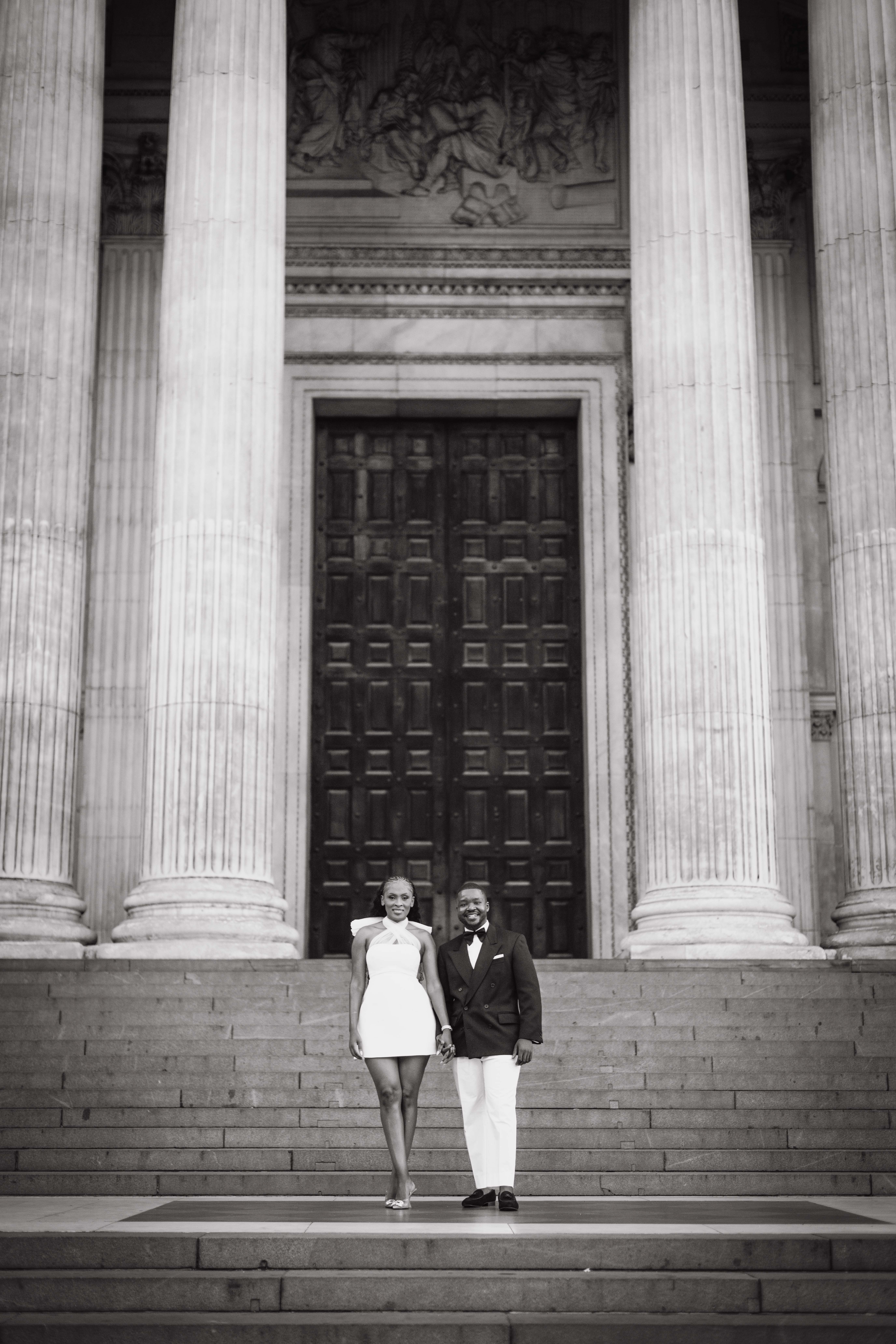 Kennedy and Didimalang holding hands on the cathedral steps, in black and white